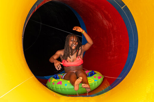 Joven sonriente en flotador en tobogán acuático en camping CAPFUN Fort Falabraque.