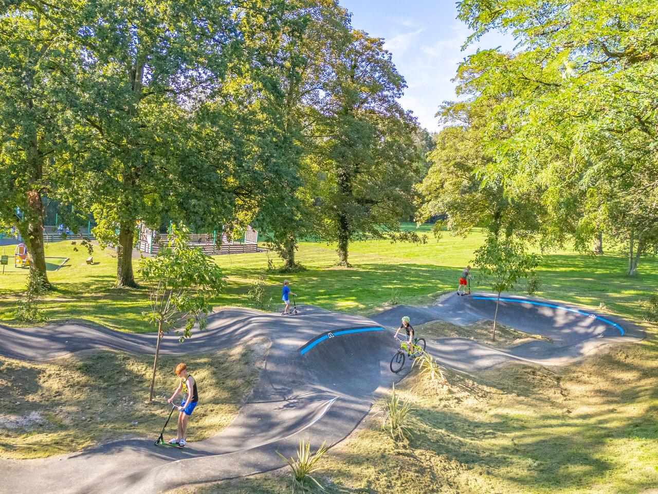 Pista de pump track moderna con ni�os en patinete y bicicleta en el camping CAPFUN Fredland en Tournan en Brie (77).