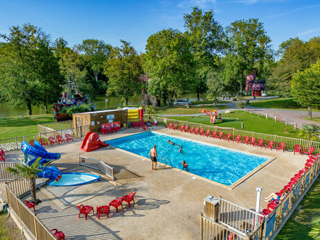 Piscina exterior, toboganes y sillas rojas en camping CAPFUN Fredland en Tournan en Brie (77).