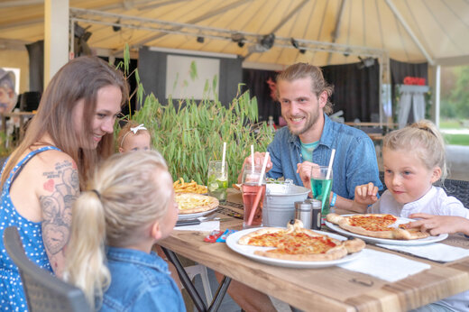Familia sonriente comiendo pizzas en el restaurante del camping CAPFUN Fredland en Tournan en Brie (77).