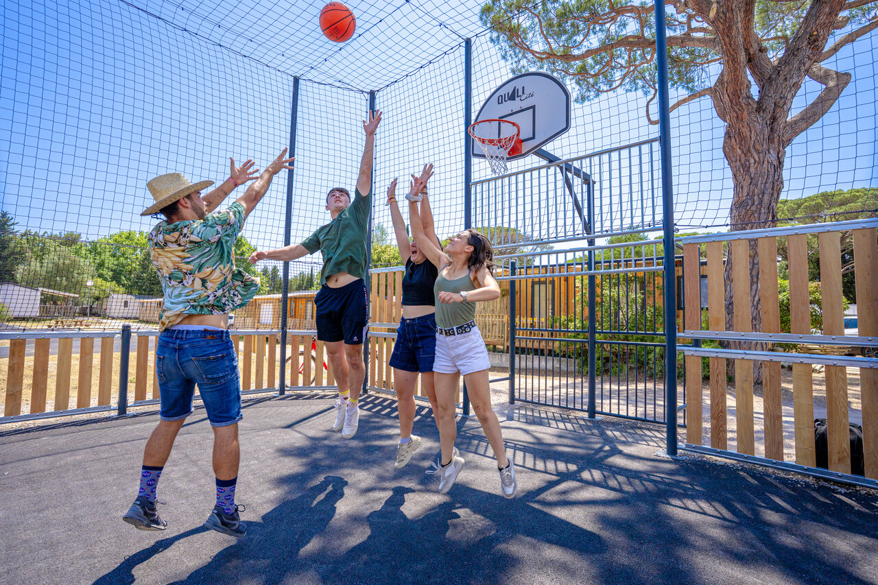 J�venes jugando baloncesto en cancha multideporte en el camping CAPFUN Le Fr�jus en Fr�jus.