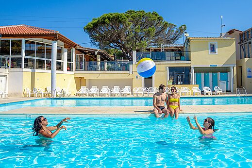 Piscina exterior con bañistas y pelota en el camping CAPFUN Le Fréjus en Fréjus.