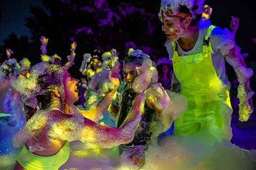 Fiesta de la espuma animada, participantes alegres, luces de colores en el camping CAPFUN Le Fréjus (83).