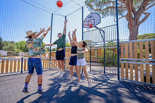 Jóvenes jugando baloncesto en la cancha multideporte del camping CAPFUN Le Fréjus (83).