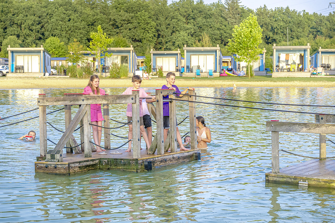 Ni�os jugando en plataforma flotante en lago, alojamientos en camping CAPFUN De Fruithof en Klijndijk.
