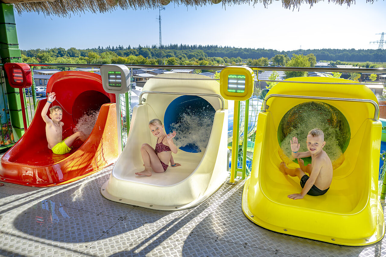 Ni�os sonrientes en los toboganes acu�ticos coloridos del camping CAPFUN De Fruithof en Klijndijk.