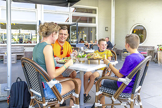 Familia cenando en la terraza del restaurante exterior en el camping CAPFUN De Fruithof.