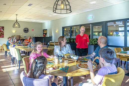 Familia cenando alegremente en el restaurante del camping CAPFUN De Fruithof en Klijndijk.
