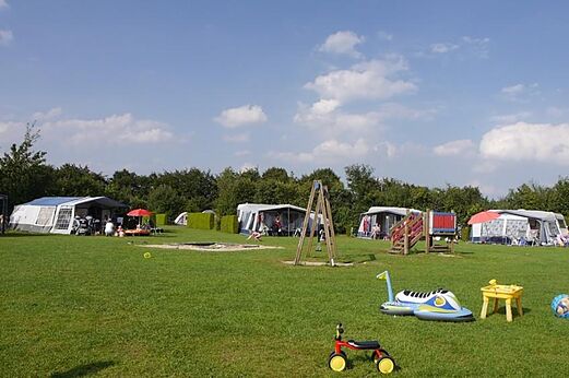 Parcela de camping con césped, zona de juegos y tiendas en el camping CAPFUN De Fruithof en Klijndijk.