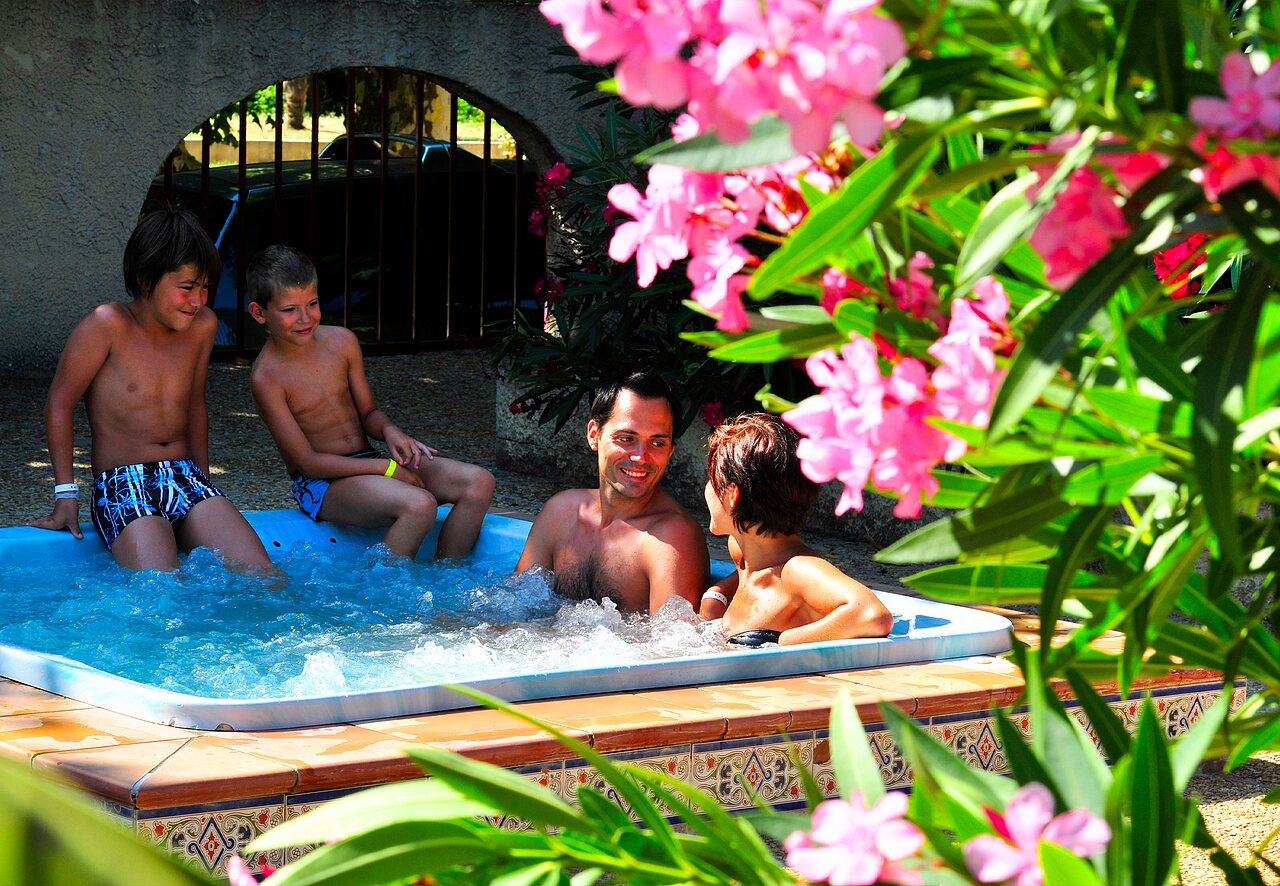 Familia sonriente disfrutando del jacuzzi burbujeante en el camping CAPFUN Fumades en ALLEGRE-LES-FUMADES (30).