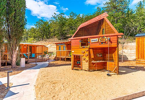 Zona de juegos de madera y Mobil-homes en el camping CAPFUN Fumades en ALLEGRE-LES-FUMADES (30).