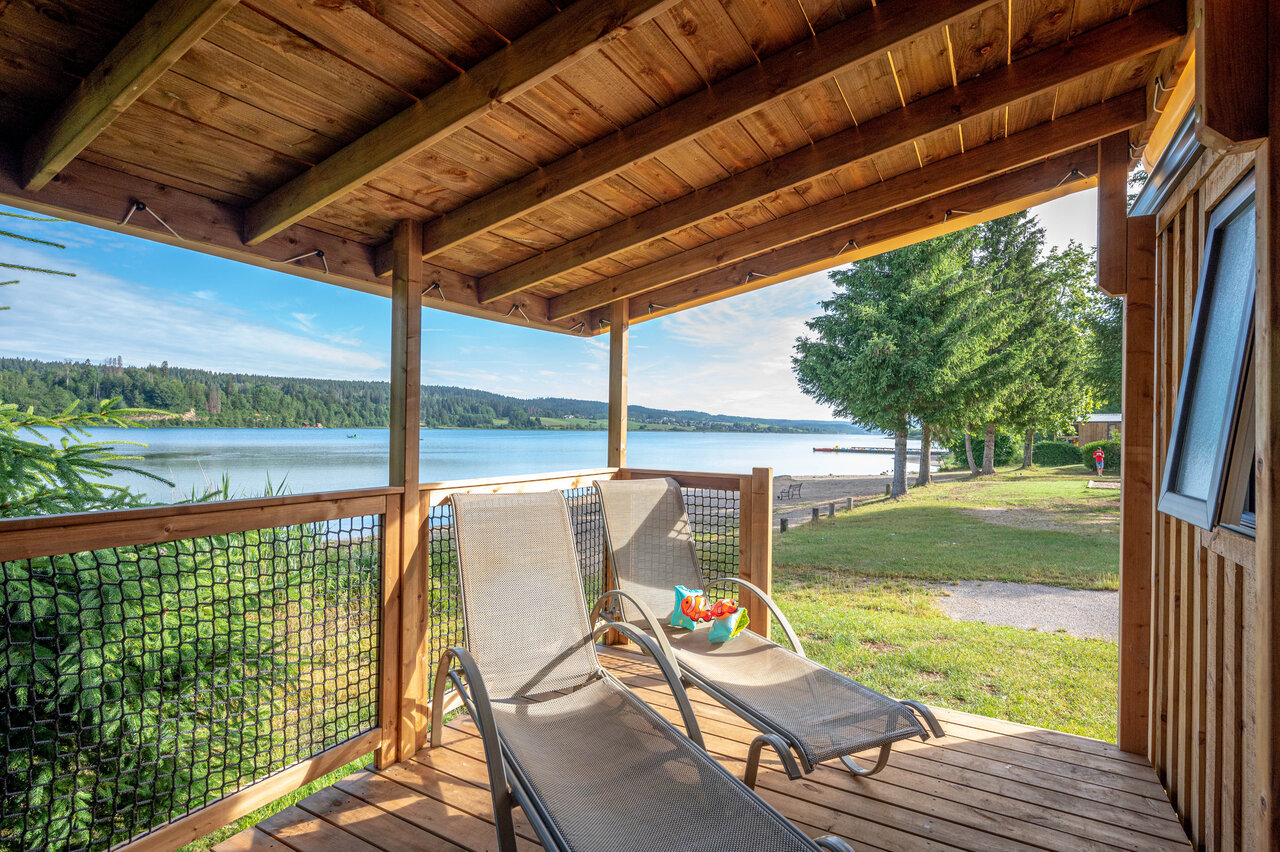 Terraza de alojamiento con tumbonas y vista al lago en el camping CAPFUN Fuvettes en Malbuisson (25).