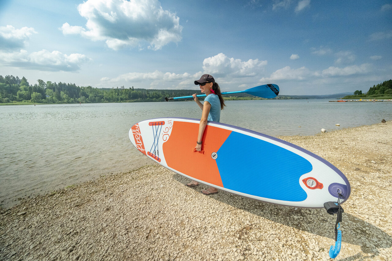 Mujer con paddleboard y remo en el lago, CAPFUN Fuvettes en Malbuisson.
