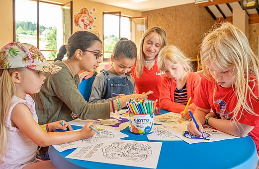 Niños coloreando con animador en actividad de camping CAPFUN Fuvettes en Malbuisson.