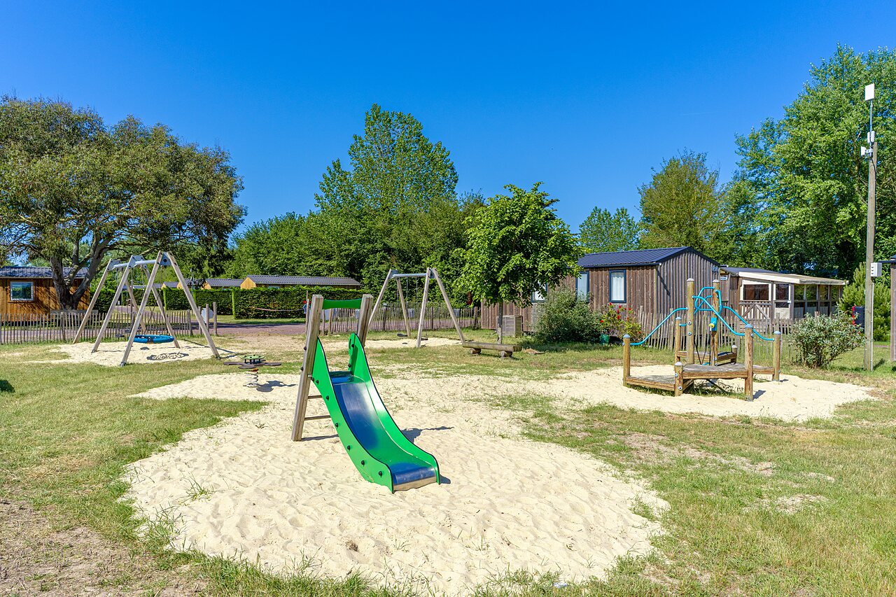Zona de juegos con tobog�n y columpios en el camping CAPFUN Golf, SAINT JEAN DE LA RIVIERE (50).