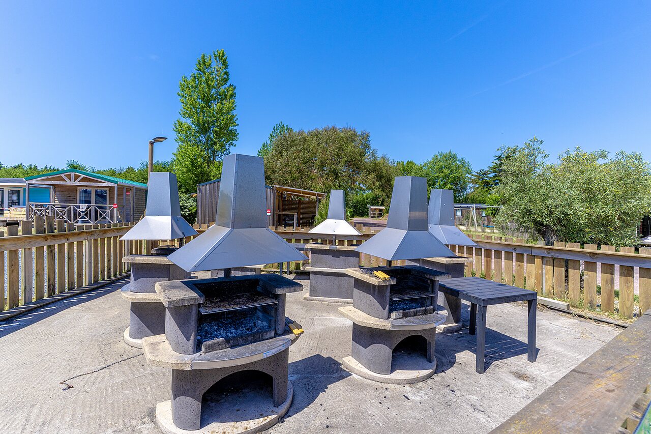 Zona de barbacoa com�n con varias parrillas en el camping CAPFUN Golf en SAINT JEAN DE LA RIVIERE (50).