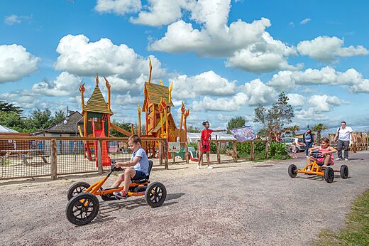 Niños en karts a pedales y zona de juegos en el camping CAPFUN Golf en SAINT JEAN DE LA RIVIERE (50).