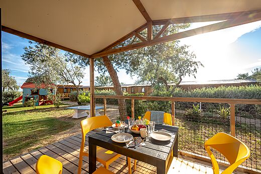 Terraza de Mobil-home con mesa y juegos infantiles en el camping CAPFUN Grande Cosse en Saint Pierre la Mer.