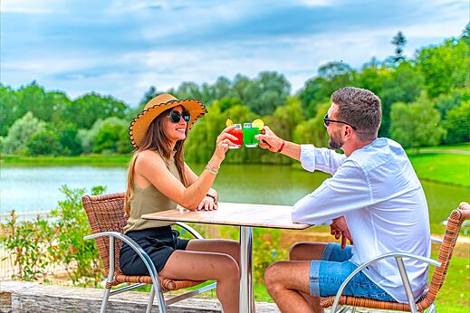 Pareja brindando cócteles en la terraza del bar en el camping CAPFUN Grand Cerf en Gimouille (58).