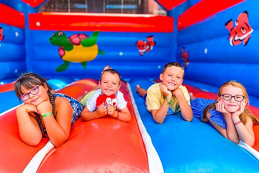 Cuatro niños sonrientes en un colorido juego inflable en el camping CAPFUN Grand Cerf en Gimouille (58).