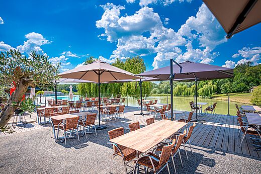Terraza de restaurante exterior, mesas, sombrillas, vista lago, CAPFUN Grand Cerf Gimouille.