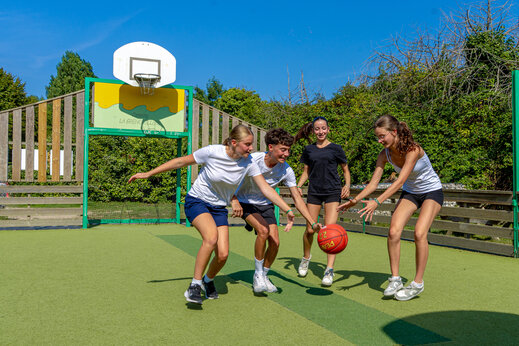 Adolescentes jugando baloncesto en cancha multideportiva en el camping CAPFUN Grenouillère en Suèvres (41).