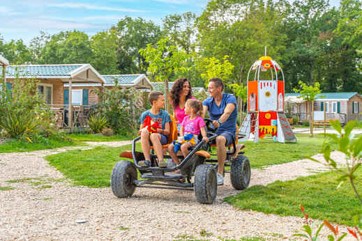 Familia en kart a pedales y parque infantil en camping CAPFUN Grenouillère en Suèvres (41).