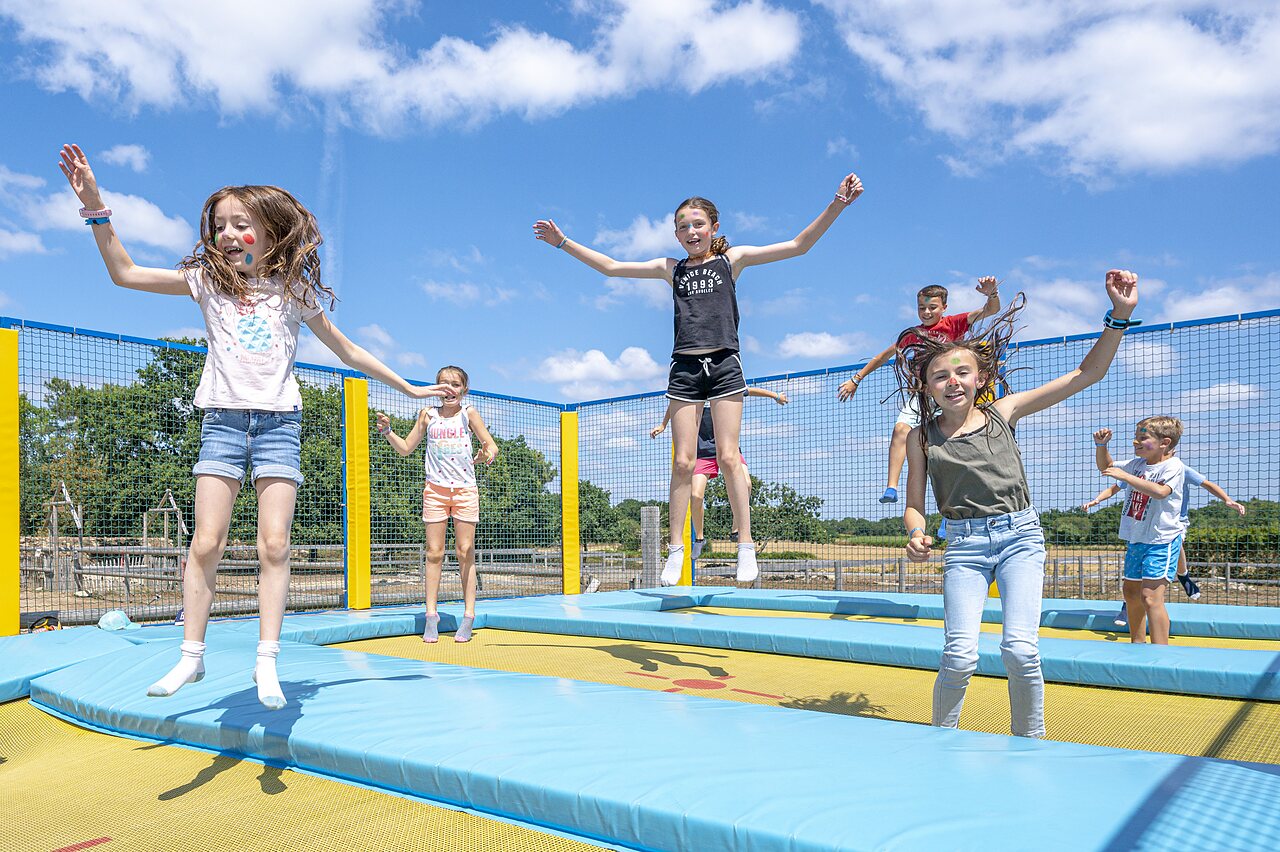 Ni�os felices saltando en los trampolines del parque de juegos en el camping CLICOCHIC Grisi�re en Clairvaux-les-Lacs (39).