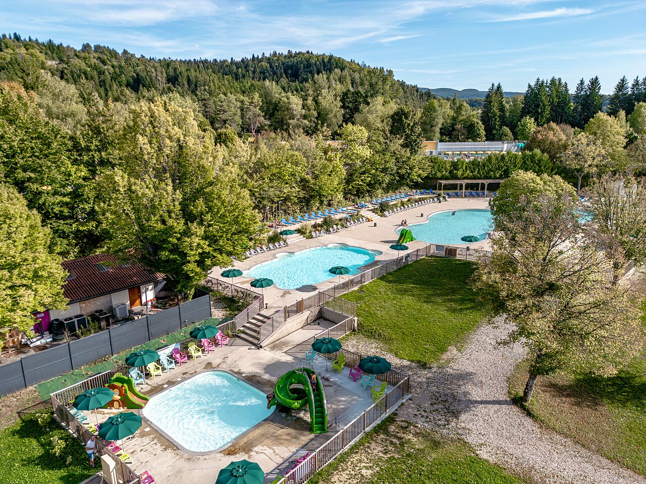 Piscinas exteriores con toboganes y tumbonas en el camping CLICOCHIC Grisi�re en Clairvaux-les-Lacs (39).