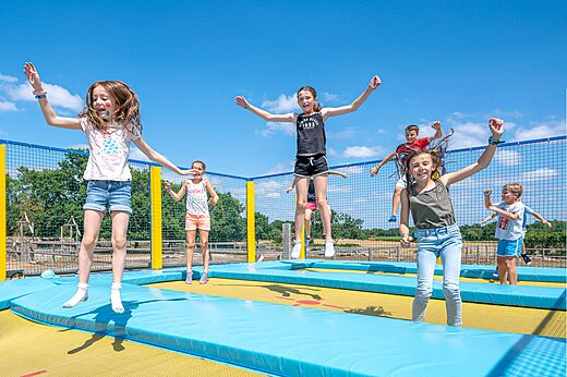 Niños saltando alegremente en los trampolines del camping CLICOCHIC Grisière en Clairvaux-les-Lacs (39).