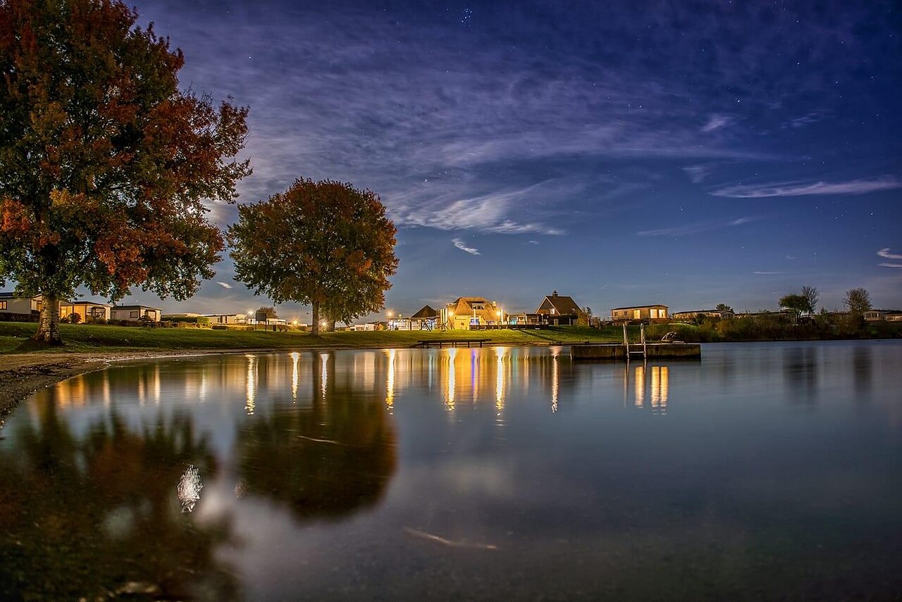 Lago iluminado de noche y alojamientos en el camping CAPFUN Groene Eiland en Appeltern.