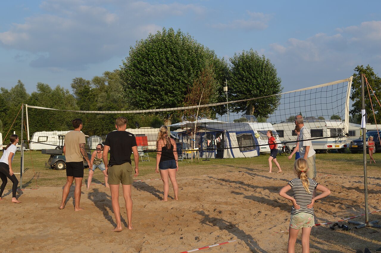 Jugadores de voleibol de playa en cancha de arena en el camping CAPFUN Groene Eiland en Appeltern.