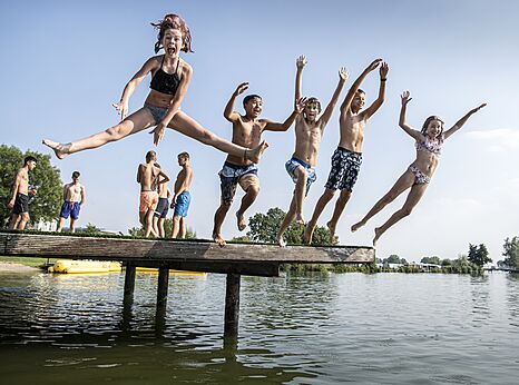 Niños saltando de plataforma al agua en camping CAPFUN Groene Eiland en Appeltern.