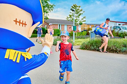 Mascota y ni�o sonriente interactuando en una animaci�n en el camping CAPFUN Groene Eiland en Appeltern.