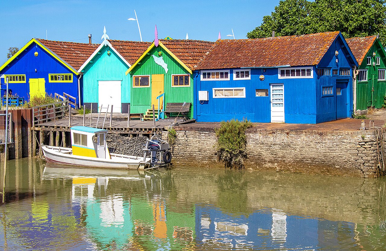 Casas coloridas y barco de pesca en un pueblo pintoresco junto al agua.