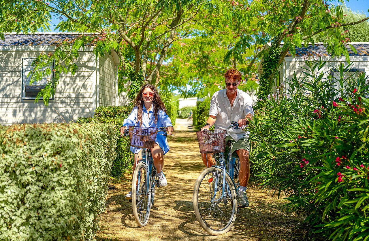 Pareja en bicicleta por sendero verde, Mobil-homes en camping VAGUES OCEANES Grosses Pierres.