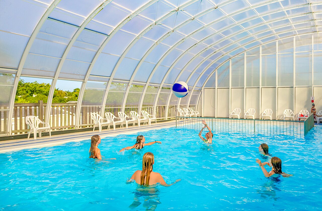 Piscina cubierta, ni�os jugando con bal�n en camping VAGUES OCEANES Grosses Pierres.