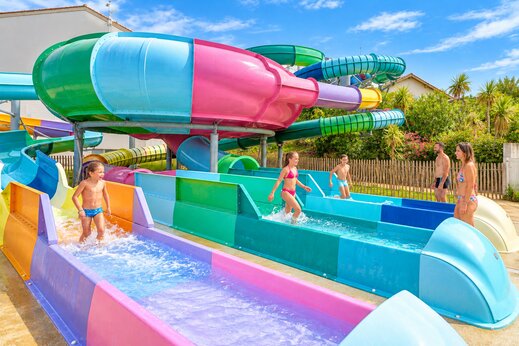 Toboganes acuáticos coloridos y niños divirtiéndose en el camping VAGUES OCEANES Grosses Pierres en Saint-Georges-d'Oléron (17).