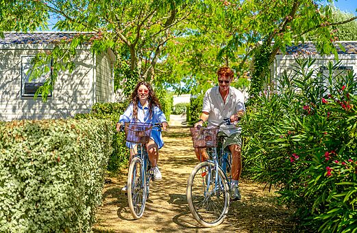 Pareja en bicicleta por sendero verde en camping VAGUES OCEANES Grosses Pierres.
