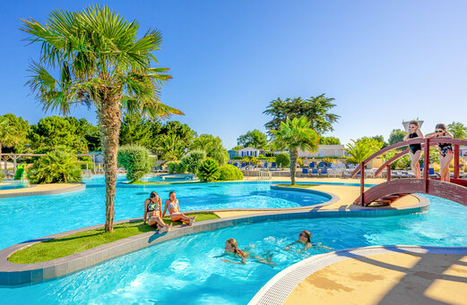 Piscina exterior, río y puente en el camping VAGUES OCEANES Grosses Pierres.