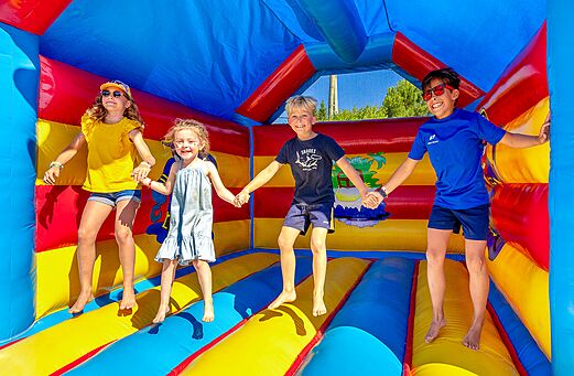 Niños felices saltando en un castillo hinchable colorido en el camping VAGUES OCEANES Grosses Pierres en Saint-Georges-d'Oléron (17).