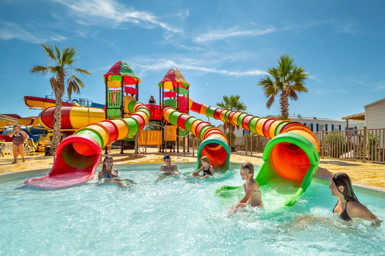Piscina, toboganes acu�ticos coloridos y ni�os en el camping VAGUES OCEANES Hamacs en Fleury.