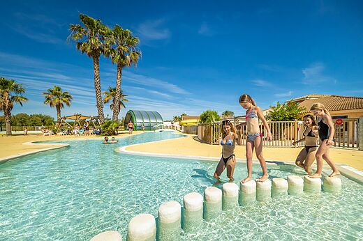 Piscina laguna con juegos acuáticos y palmeras en el camping VAGUES OCEANES Hamacs en Fleury (11).