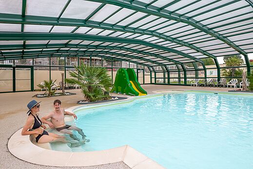 Piscina cubierta, tobog�n acu�tico y pareja en el camping CLICOCHIC Haras de Deauville.