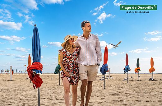 Playa de Deauville con sombrillas coloridas y pareja, lugar para visitar en Normand�a.