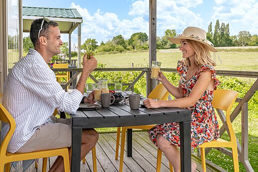 Pareja desayunando en la terraza de un Mobil-home en el camping CLICOCHIC Haras de Deauville en Touques.