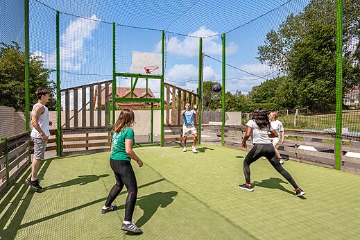 Jóvenes jugando baloncesto en cancha multideportiva en el camping CLICOCHIC Haras de Deauville.