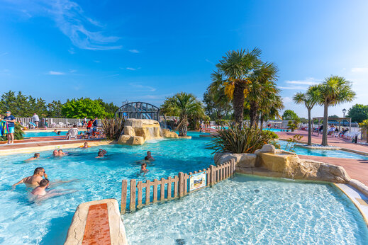 Piscina exterior, cascada y palmeras en el camping CAPFUN Hautes Coutures en BENOUVILLE (14).