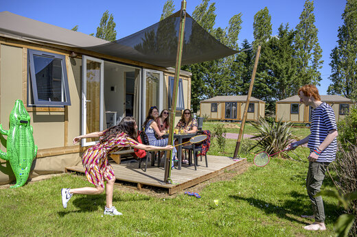 Mobil-home moderno con terraza, familia jugando bádminton en camping CAPFUN Hautes Coutures.