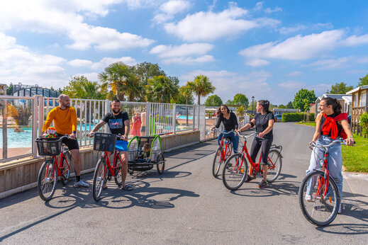 Familia en bicicleta con remolque para niños en el camping CAPFUN Hautes Coutures en BENOUVILLE (14).